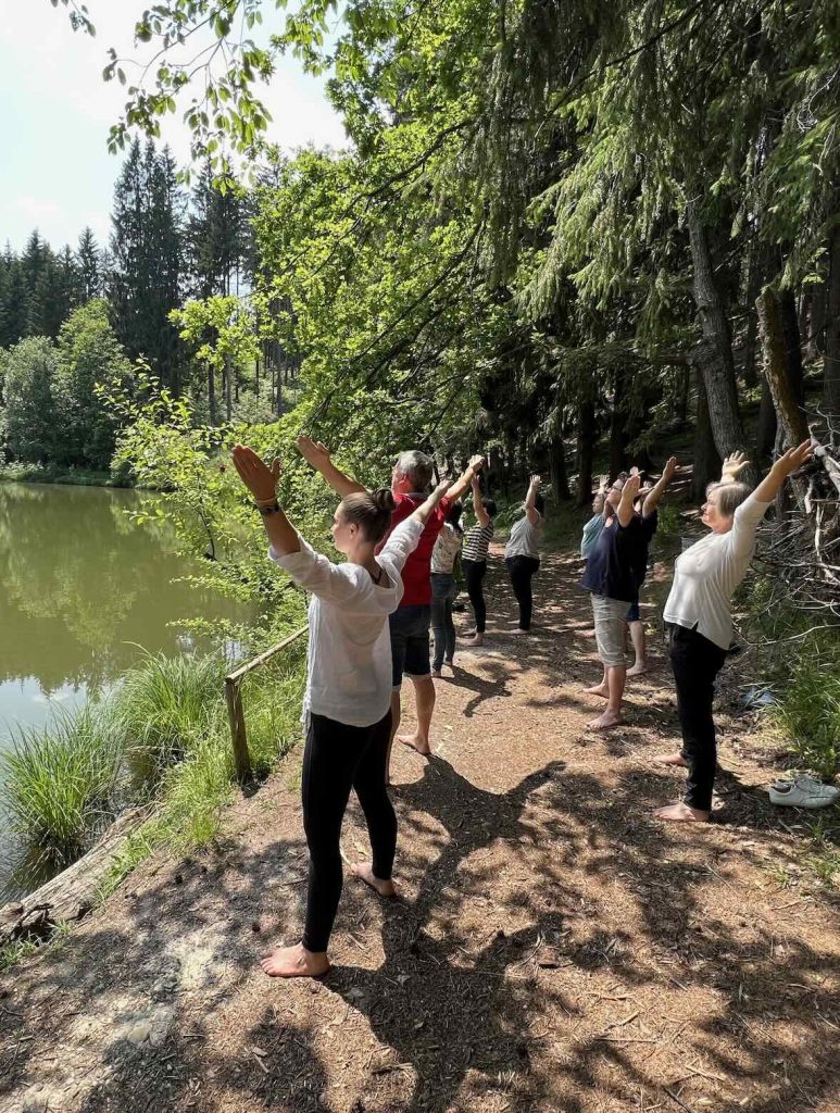 Seminarteilnehmer machen Asanas im Wald